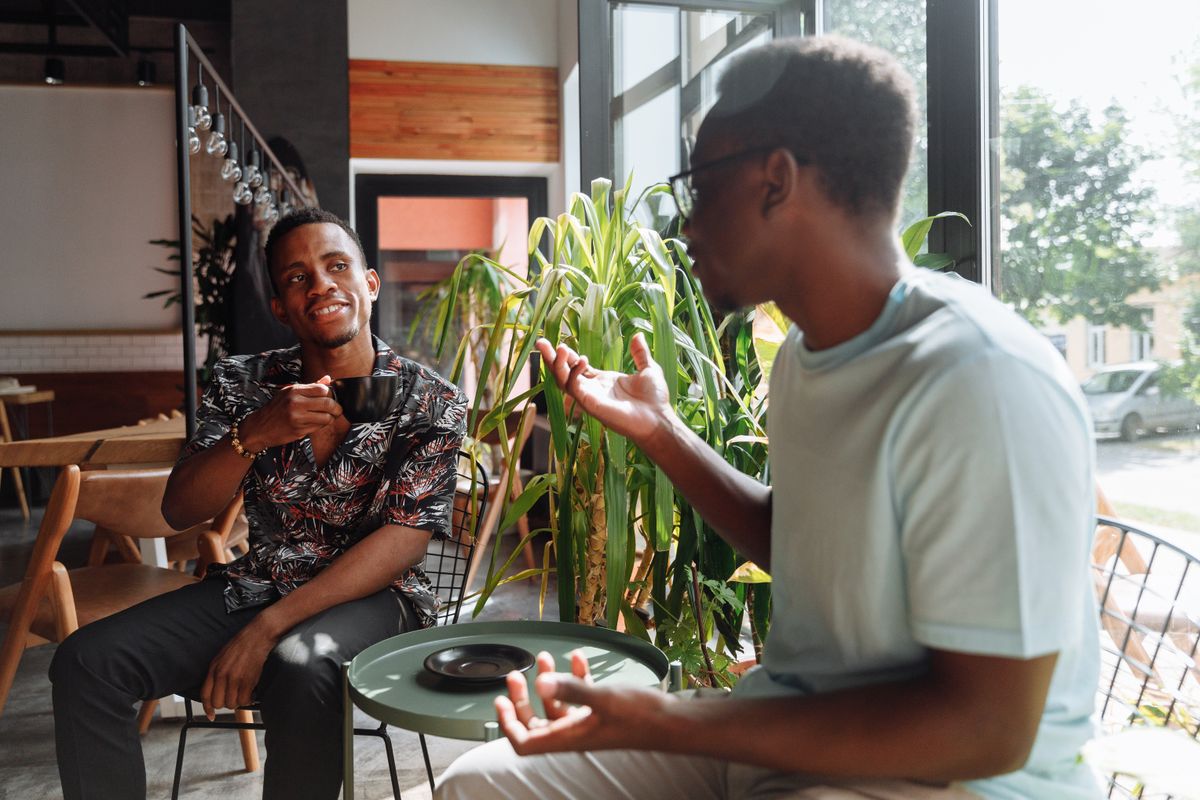 Two people having a warm conversation at a cafe, looking at a tablet together — representing NDIS plan management support