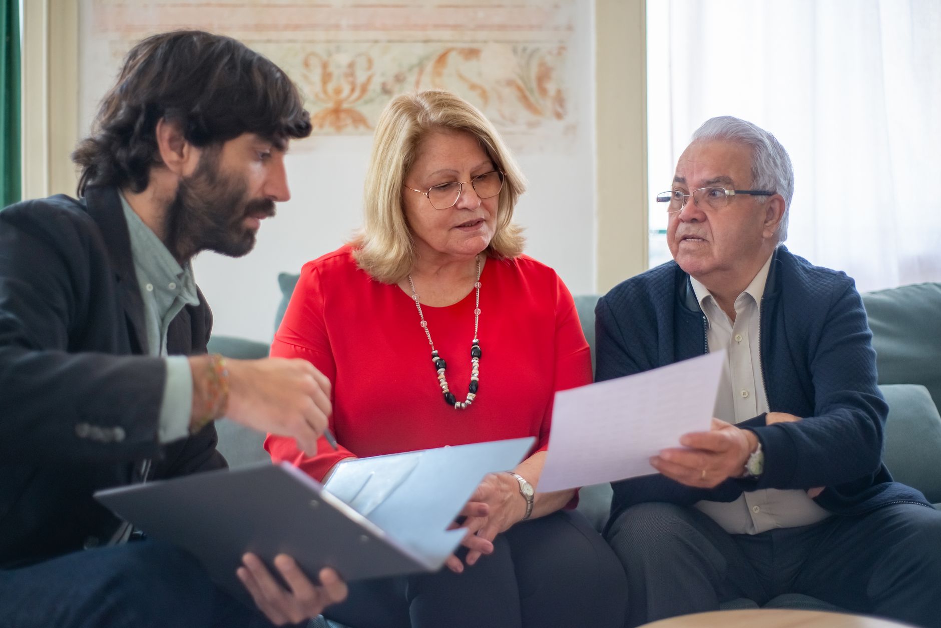 Senior couple consulting with professional advisor, reviewing documents at a table — stock photo