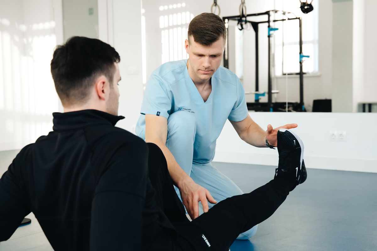 A physiotherapist working with a client on mobility exercises in a bright, modern clinic space
