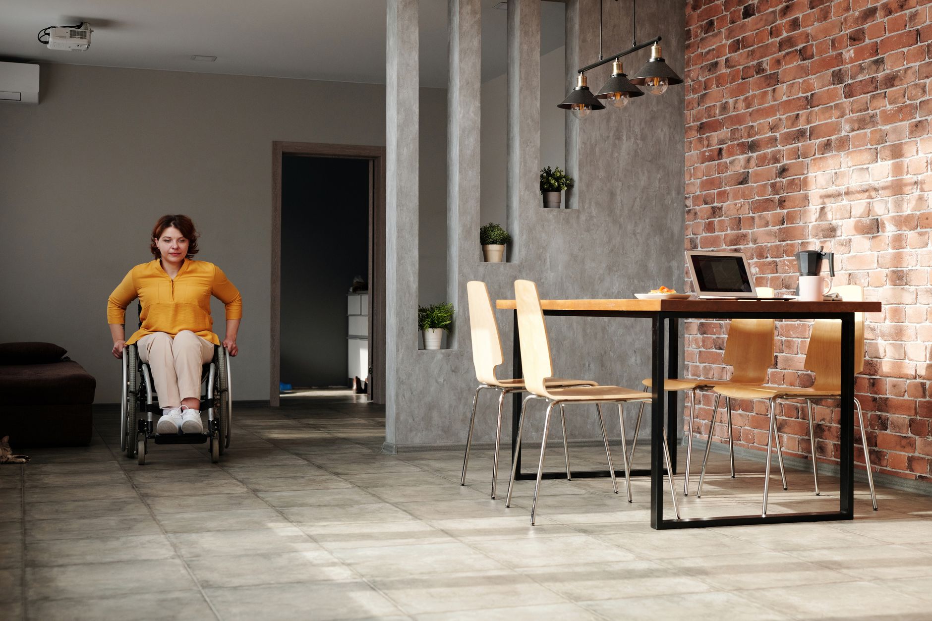 Woman in wheelchair in a bright, clean modern apartment — representing independent living supported by NDIS domestic assistance