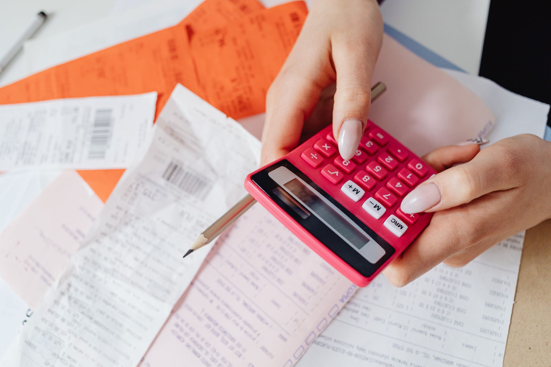 Hands using a calculator to review expenses, representing checking NDIS invoices against price limits