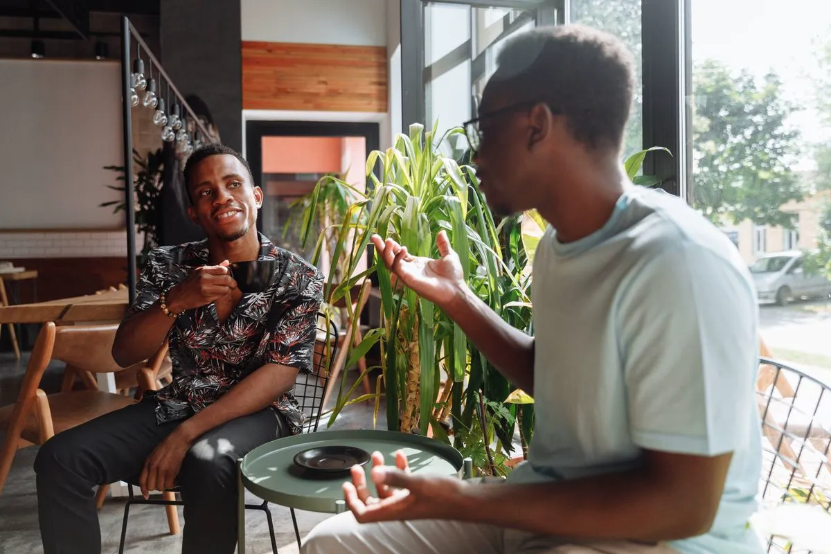 Two friends sharing a lively conversation over coffee in a warm, modern cafe
